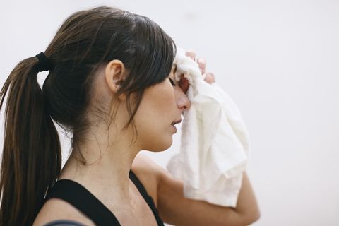 young woman wiping off sweat from her forehead