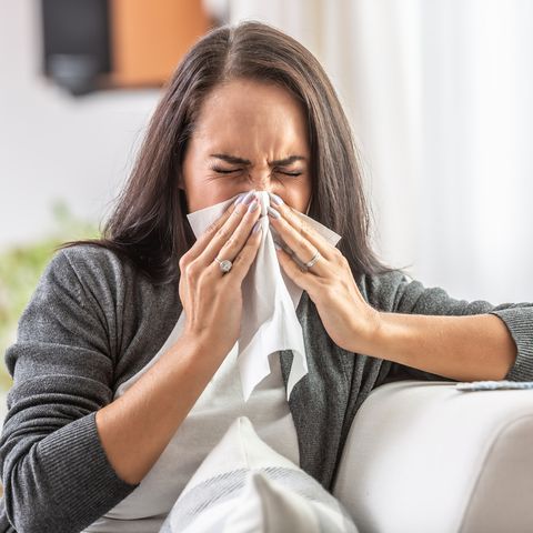 young woman with a flu sneezes and cleans her nose