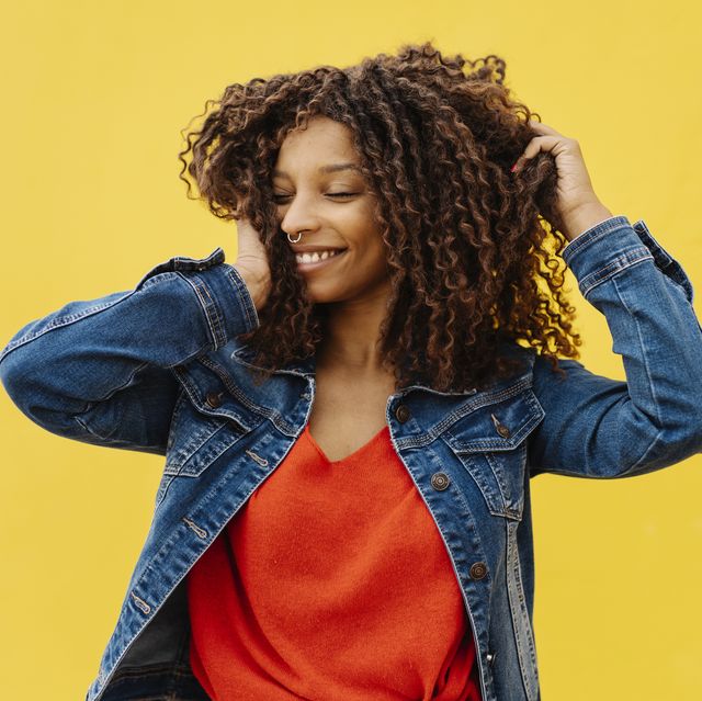 young woman with african roots and curly hair posing and smiling