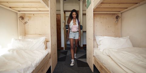 Young woman with backpack, arriving at empty hostel room