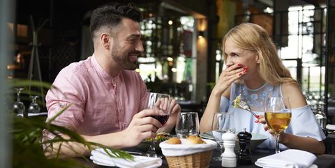 Young woman with boyfriend laughing at restaurant table
