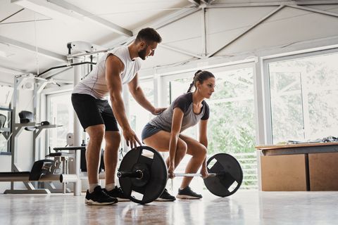 young woman with instructor preparing for deadlift