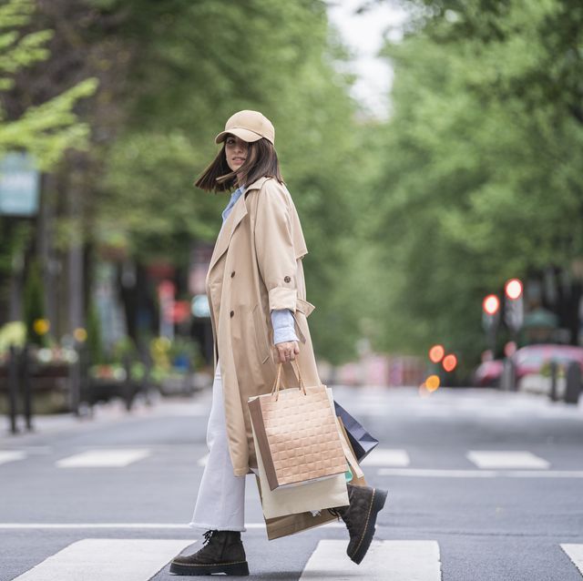 young woman with shopping bags walking on road
