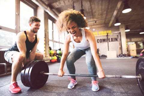 Young woman with training partner preparing to lift barbell in gym Young woman with training partner preparing to lift barbell in gym
