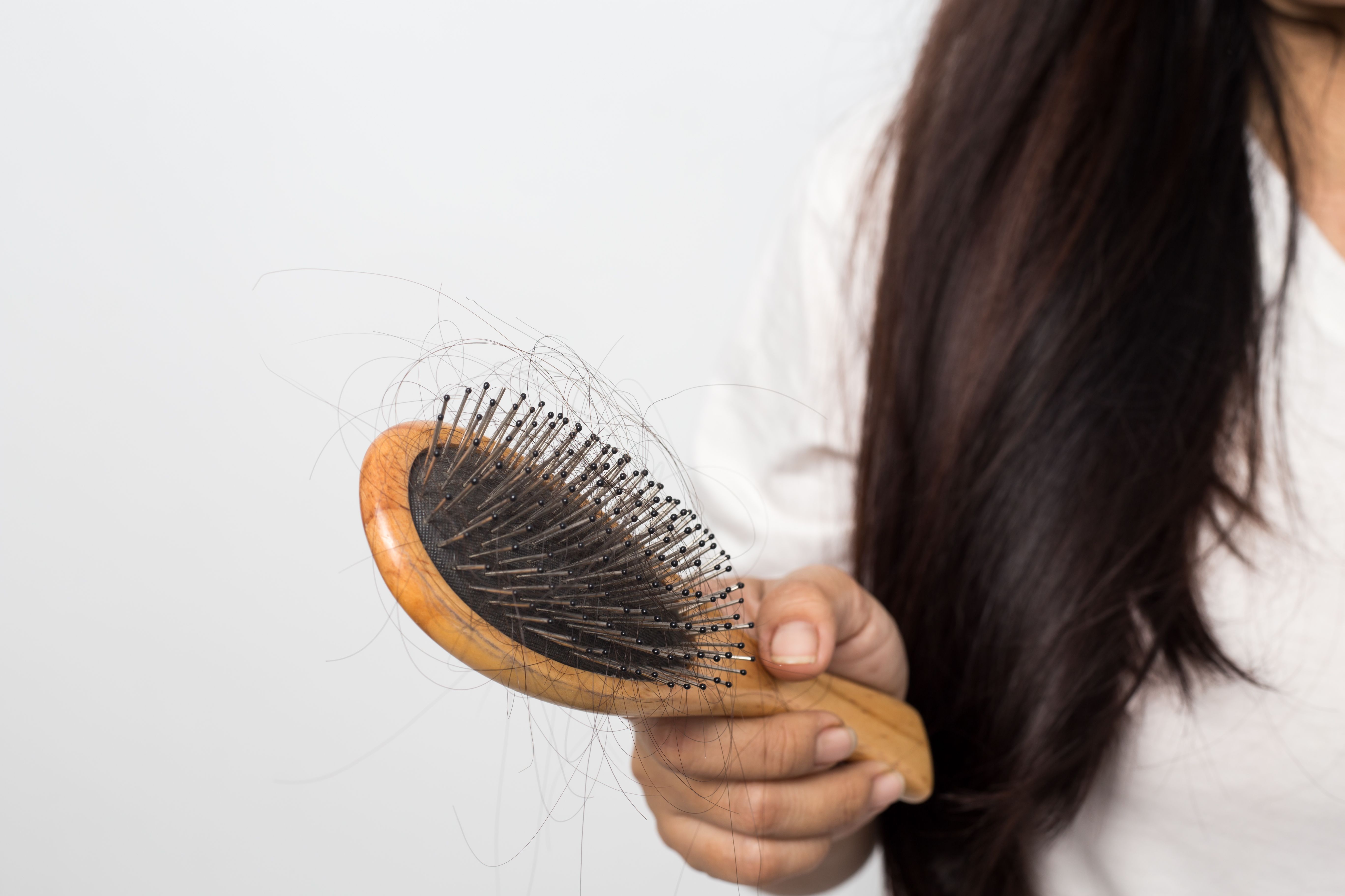 У женщины очень сильно выпадают волосы. Расческа для волос. Выпадение волос расчес.