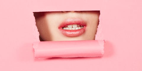 Young womans mouth through cutout in pink paper