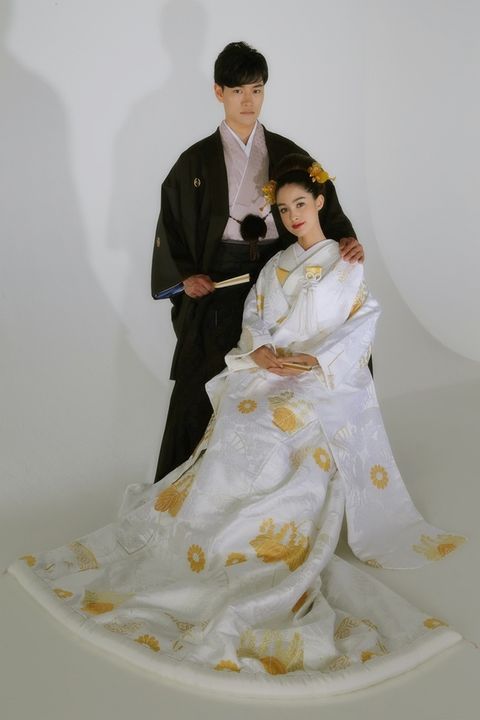 桂由美ブライダルハウスの金の刺しゅう入りの白無垢を着たモデルと紋付き袴を着た男性モデルが並んでいる写真。