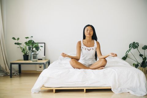Young woman practicing yoga on bed
