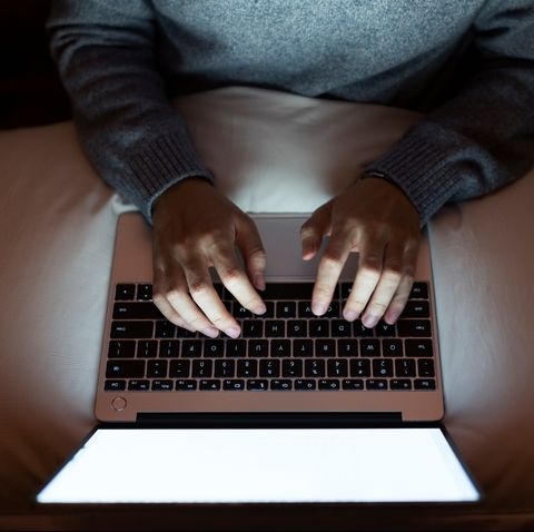 a woman in the dark using her laptop in bed