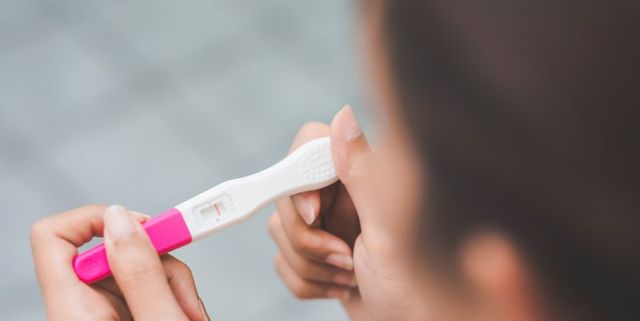 vrouw checkt of ze zwanger is met zwangerschapstest in haar hand