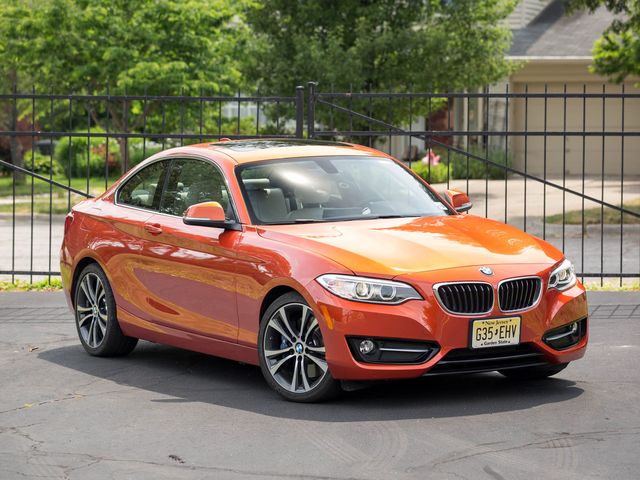 2017 orange bmw 2 series coupe parked in front of a wrought iron fence