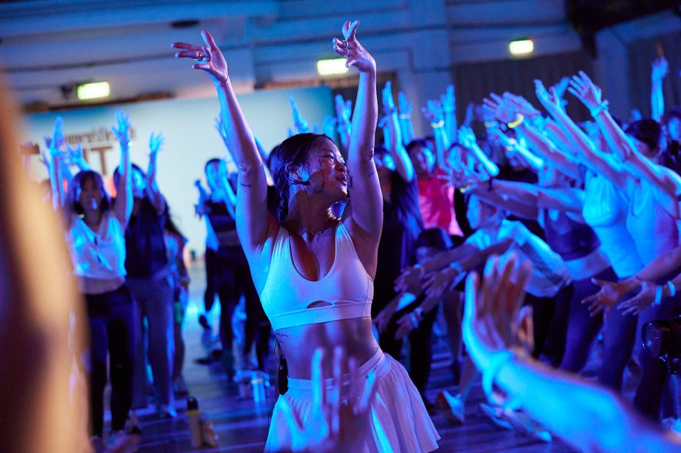 a person in a white dress dancing in a room full of people