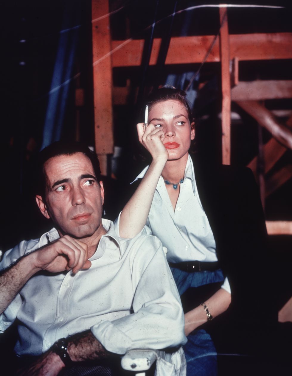 Lauren Bacall smoking a cigarette and leaning on the shoulder of  Humphrey Bogart on the set of the film 'Key Largo.'