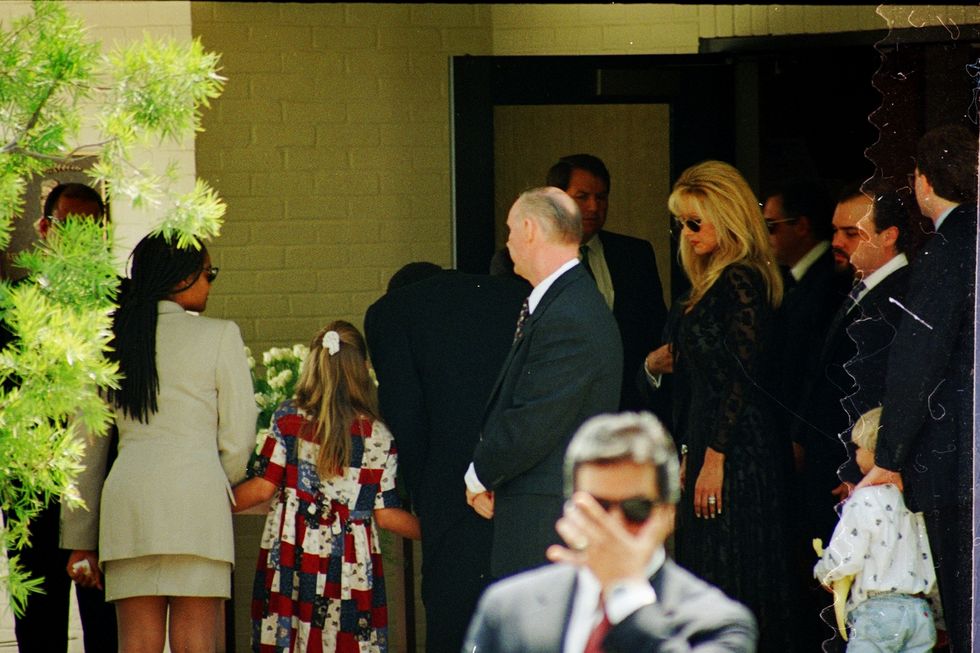 oj simpson and children walk outside a building as other people walk nearby