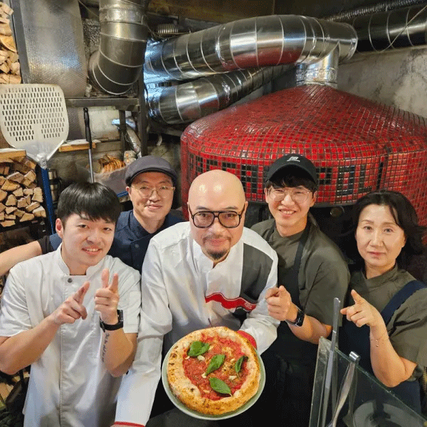 a group of people posing for a photo with a pizza