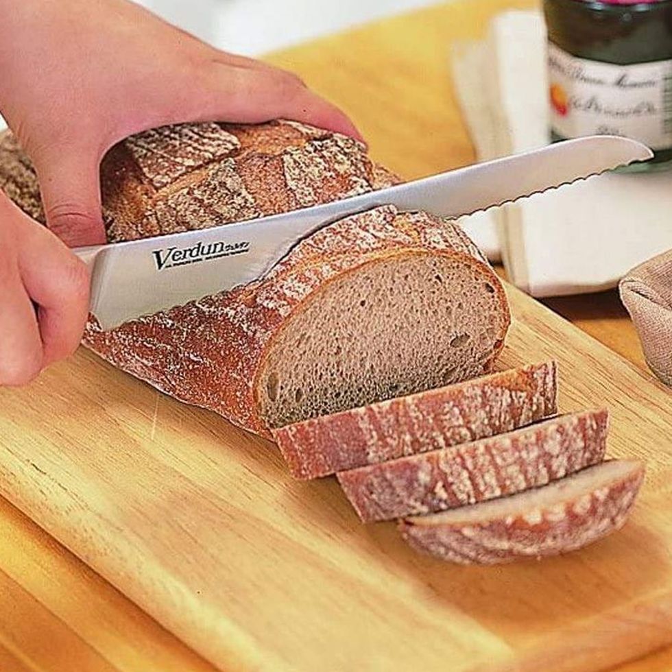 a person cutting a loaf of bread