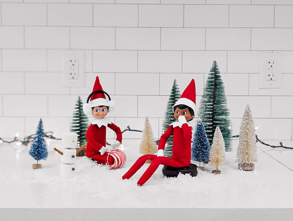 two elves in a winter scene, and one is sledding on a candy cane sled