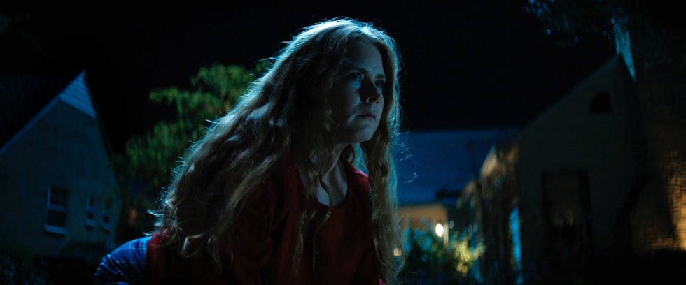 a woman with long hair in a red garment in a nighttime outdoor setting