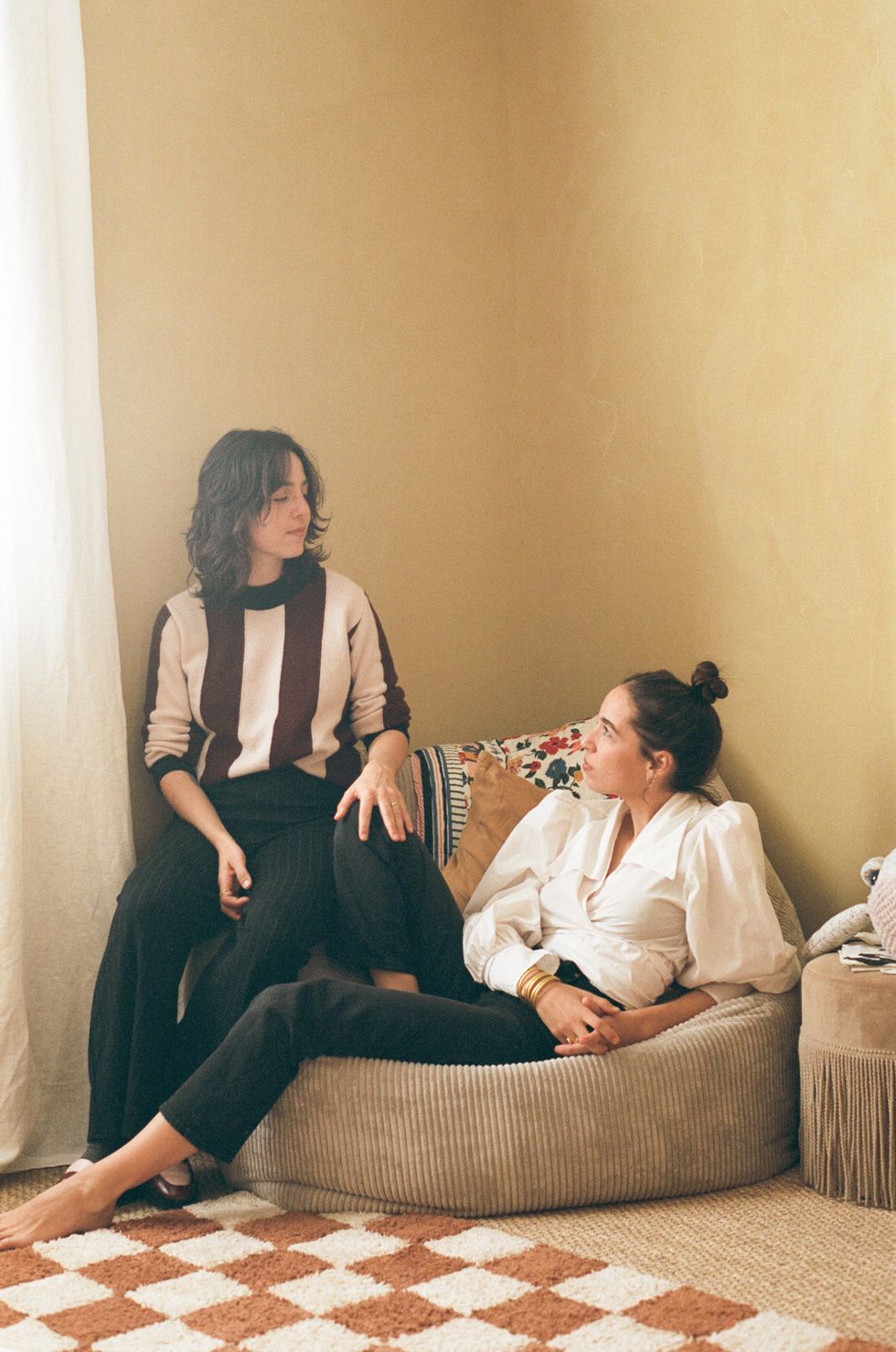 a person sitting on a couch with another woman sitting on the couch