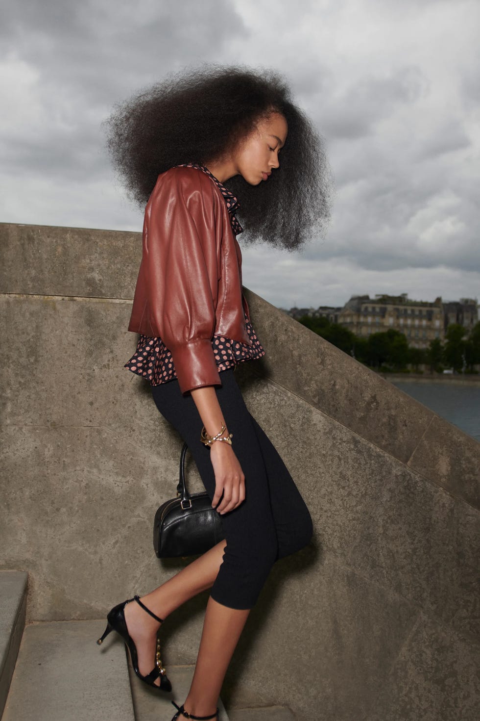 a stylish figure in a chic outfit walking down stairs beside a body of water
