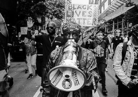 man holding bull horn looks into camera while marching with other protestors