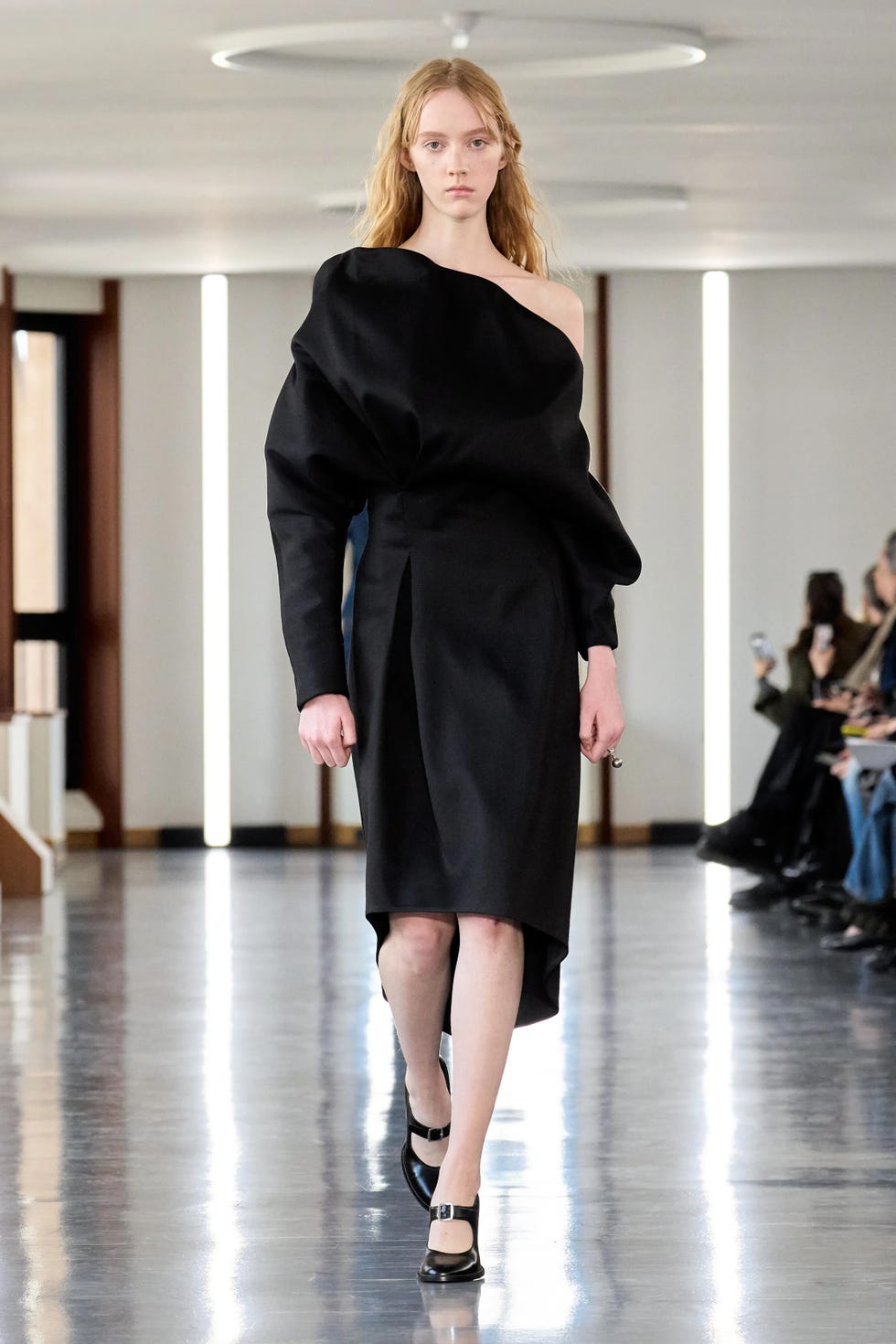 model walking down a runway in a black fashion dress