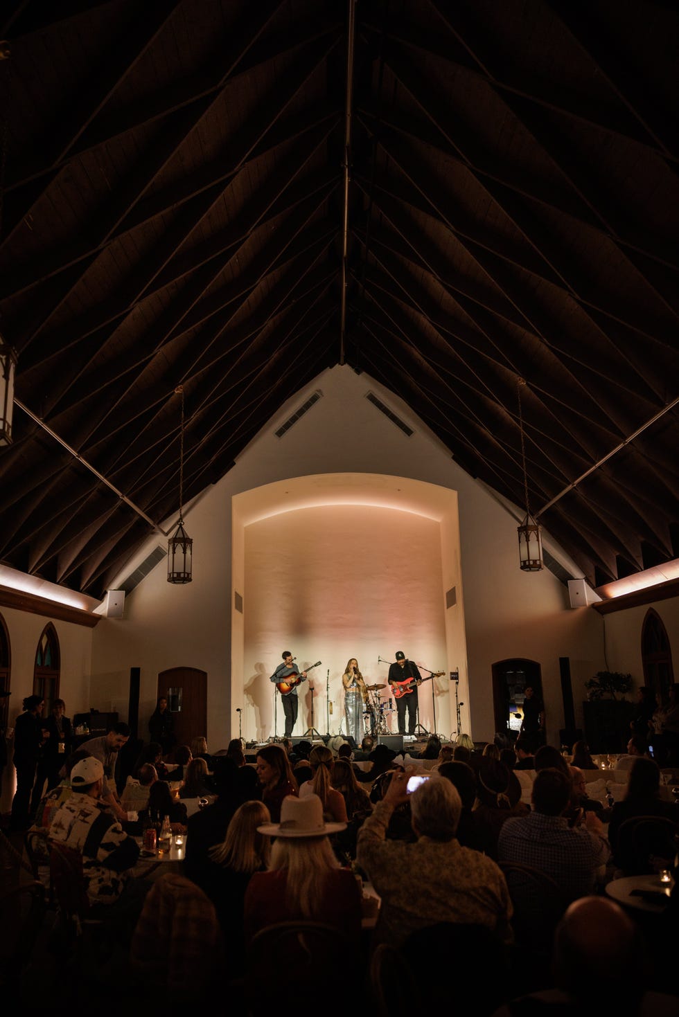 live music performance in a venue with a high ceiling and warm lighting