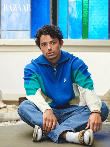 anthony sits on the ground in a blue zipup and jeans