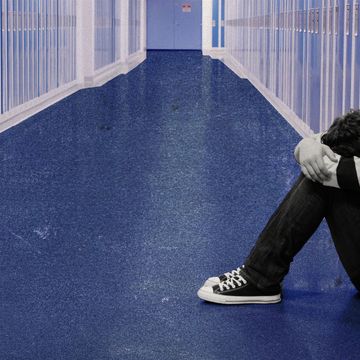 young teen sitting with his head between his knees in a high school hallway
