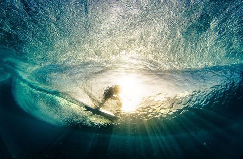 MUARA SIBERUT WESTSUMATRA INDONESITerwijl een surfer over het wateroppervlak glijdt verandert de zon de oceaan in een visioen van gebrandschilderd glas