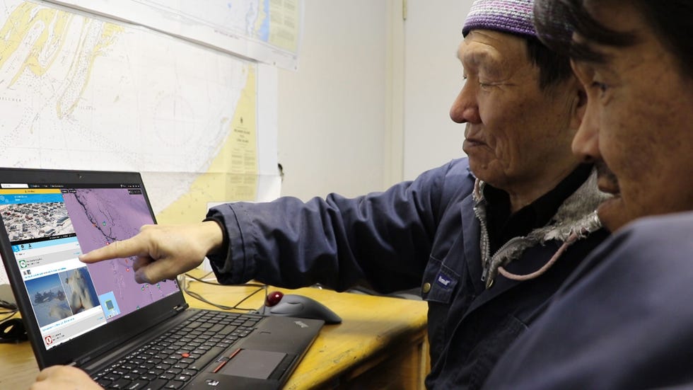 De ouderlingen Jimmy Iqaluit en Hunter Johnny Kurluarok lezen posts op het onlineplatform SIKU dat is opgezet om de toestand van het pakijs bij te houden