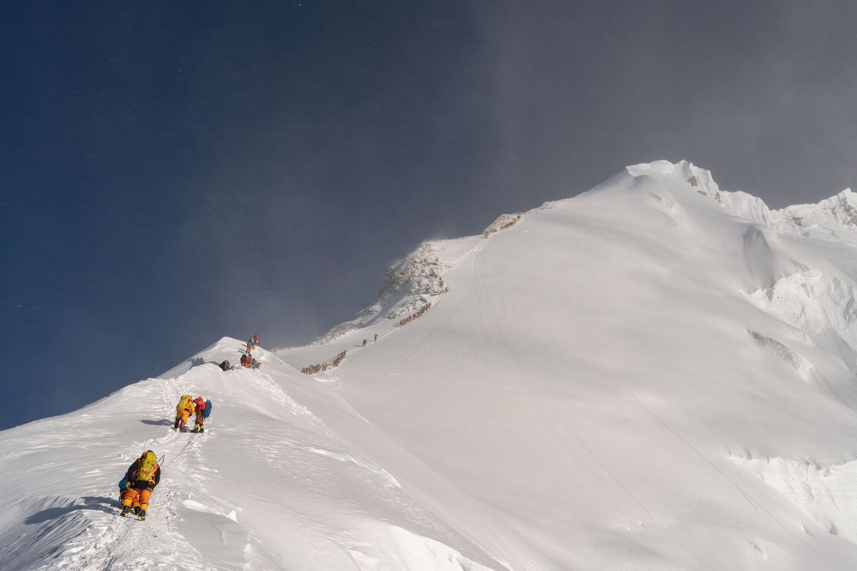 Klimmers staan in mei 2019 in de rij om richting de top van de Everest te gaan De stroom mensen die jaarlijks de top van de berg beklimt laat onbedoeld sporen achter op de berg in de vorm van kleine sliertjes plastic die afkomstig zijn van synthetische materialen die veel in outdoorkleding worden gebruikt