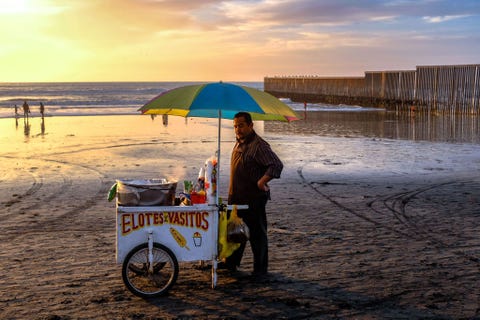TIJUANA MEXICOAan het uiterste uiteinde van de grens van Mexico met de VS op Playa de Tijuana verkoopt een strandventer elotes maskolven met limoensap room kaas en kruiden aan hongerige badgasten