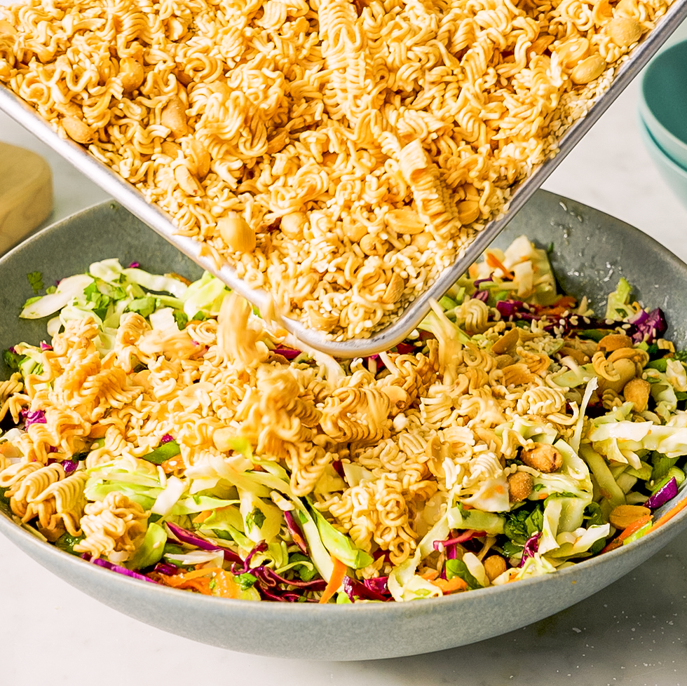 tossing fried ramen noodles into a vegetable salad