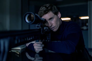 a person aiming a sniper rifle while resting on a table