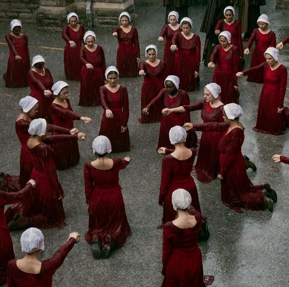 Still of multiple Handmaids pointing to a person in the centre