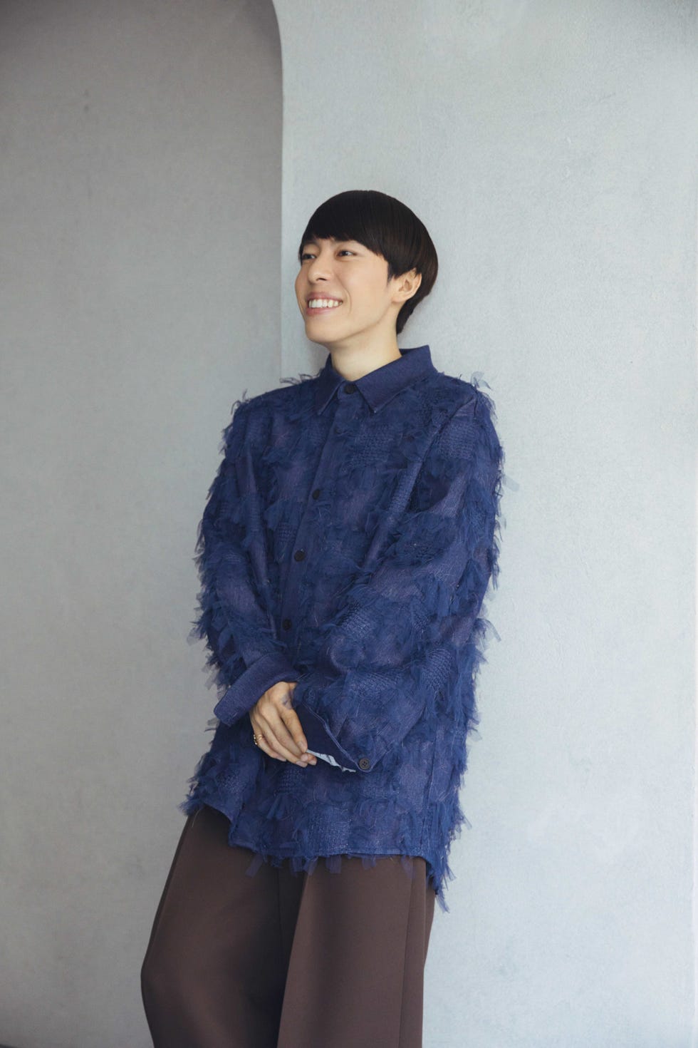 a woman smiling and wearing a blue sweater