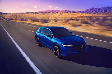 a blue suv driving on an empty asphalt road with a desert landscape and mountains in the background