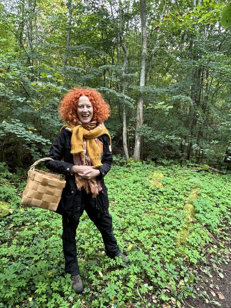 a person with red hair and a bag walking through a forest