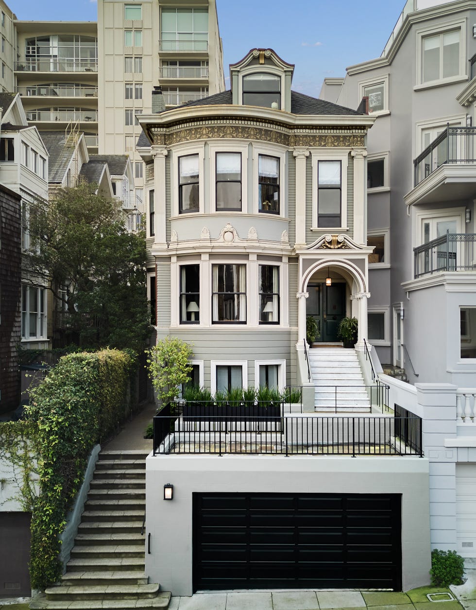 victorianstyle house with modern buildings in the background featuring a landscaped front yard and garage