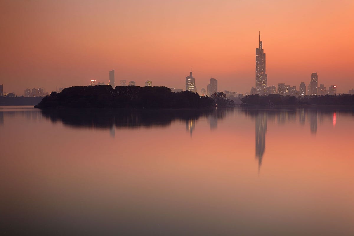 De ondergaande zon omlijst de skyline van Nanjing die verrijst boven het Ziwumeer in China