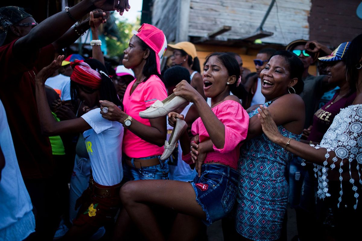 Een groep mensen danst in een volgepakte straat tijdens een feestdag op het eiland