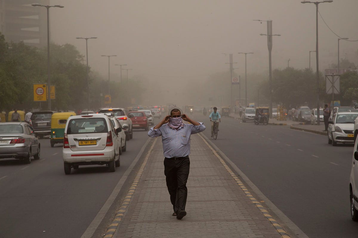 Een man slaat een sjaal voor zijn gezicht tijdens een zandstorm in de stad New Delhi in India