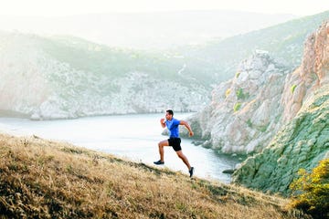 male runner running uphill in background sea bay