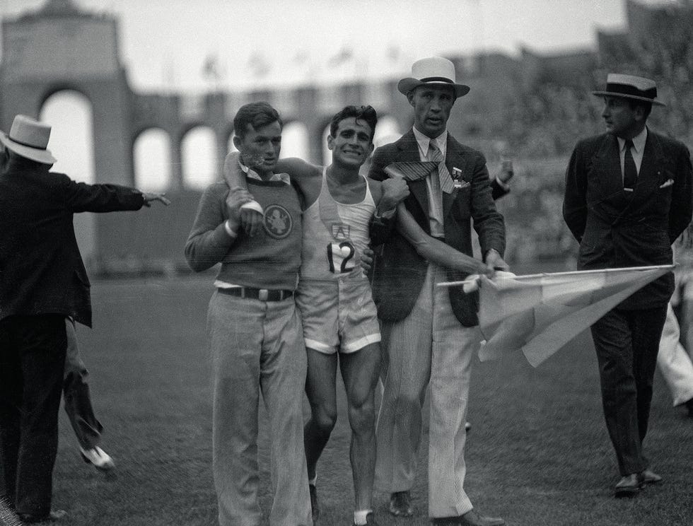 (original caption) 8/9/1932 los angeles, ca supported by officials, juan zabala of argentina holds the flag of his country and sobs after winning the marathon event of the los angeles olympic games.