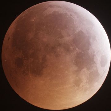 Een wit lichtstipje helemaal links markeert de plek waar een meteoor inslaat op de maan tijdens een volledige maansverduistering op 20 januari