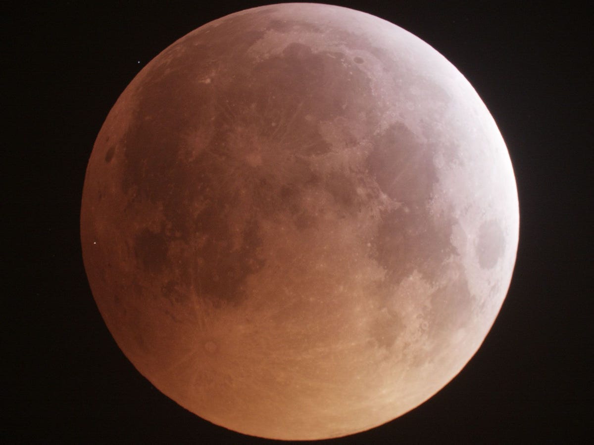 Een wit lichtstipje helemaal links markeert de plek waar een meteoor inslaat op de maan tijdens een volledige maansverduistering op 20 januari