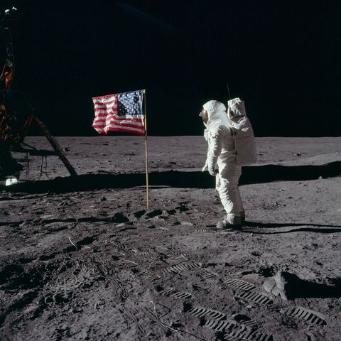 Apollo 11astronaut Edwin Buzz Aldrin poseert met de Amerikaanse vlag die in de Mare Tranquillitatis op de maan is geplant Wie goed kijkt kan Aldrins gezicht door het vizier van zijn helm ontwaren