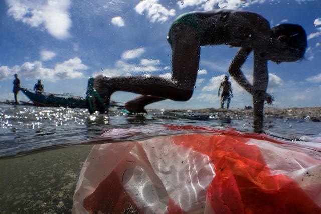 Kinderen spelen op het strand van de Baai van Manilla die ernstig is verontreinigd met huisvuil plastic en ander afval