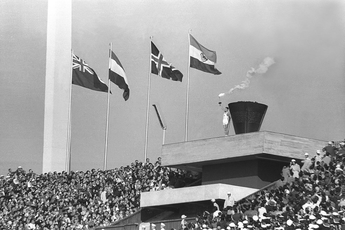 Yoshinori Sakai de laatste drager van de olympische fakkel poseert tijdens de openingsceremonie van de Olympische Spelen van 1964 in Tokio Het was de eerste keer dat het land de Spelen organiseerde ondanks dat Tokio de beurt eerder in 1940 ten deel was gevallen Toen werden de Spelen afgelast vanwege de Tweede Wereldoorlog